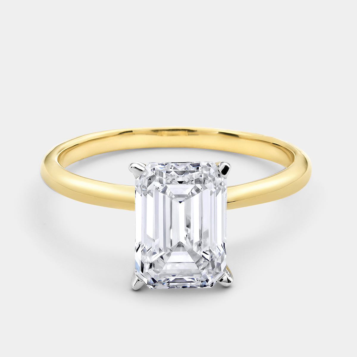 The GRACE Emerald Solitaire Ring by Keemti Jewels features a gold band with a large emerald-cut diamond in four prongs.