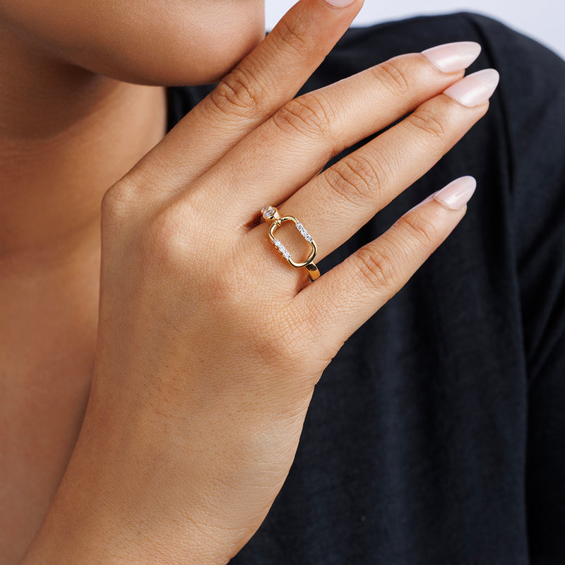A manicured hand wears the Keemti Jewels CONTOUR Link RING with yellow plating and clear stones against a dark shirt.