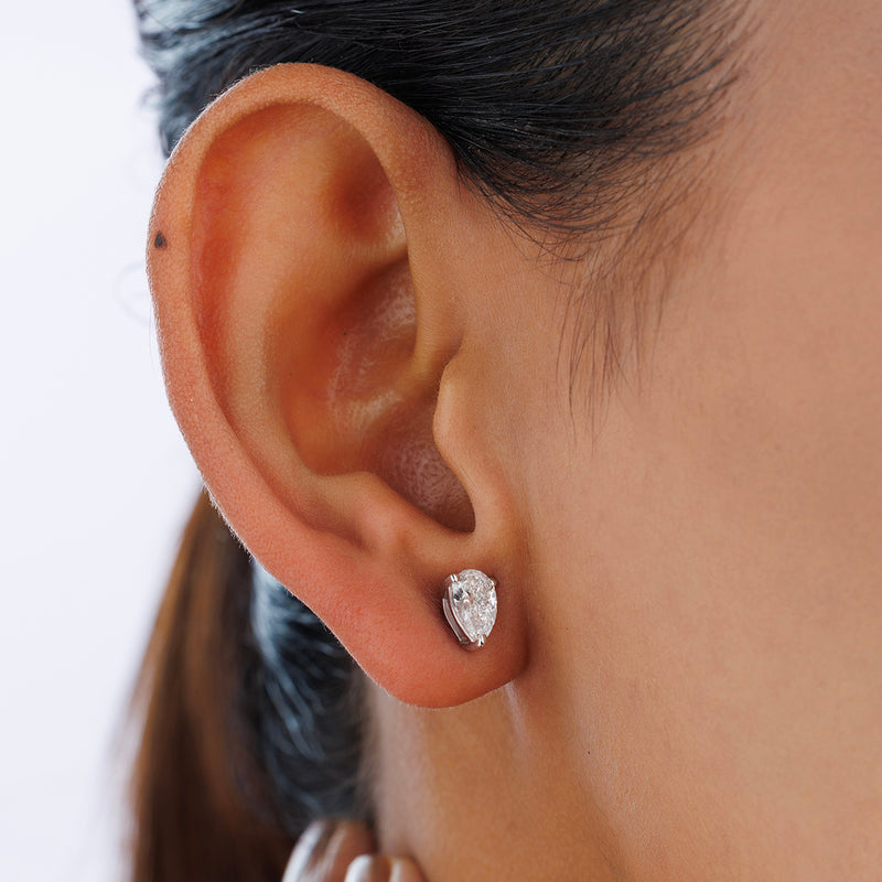 A close-up of a woman's ear wearing Keemti Jewels PEARLUXE Solitaire Stud Earrings in a prong and basket setting.