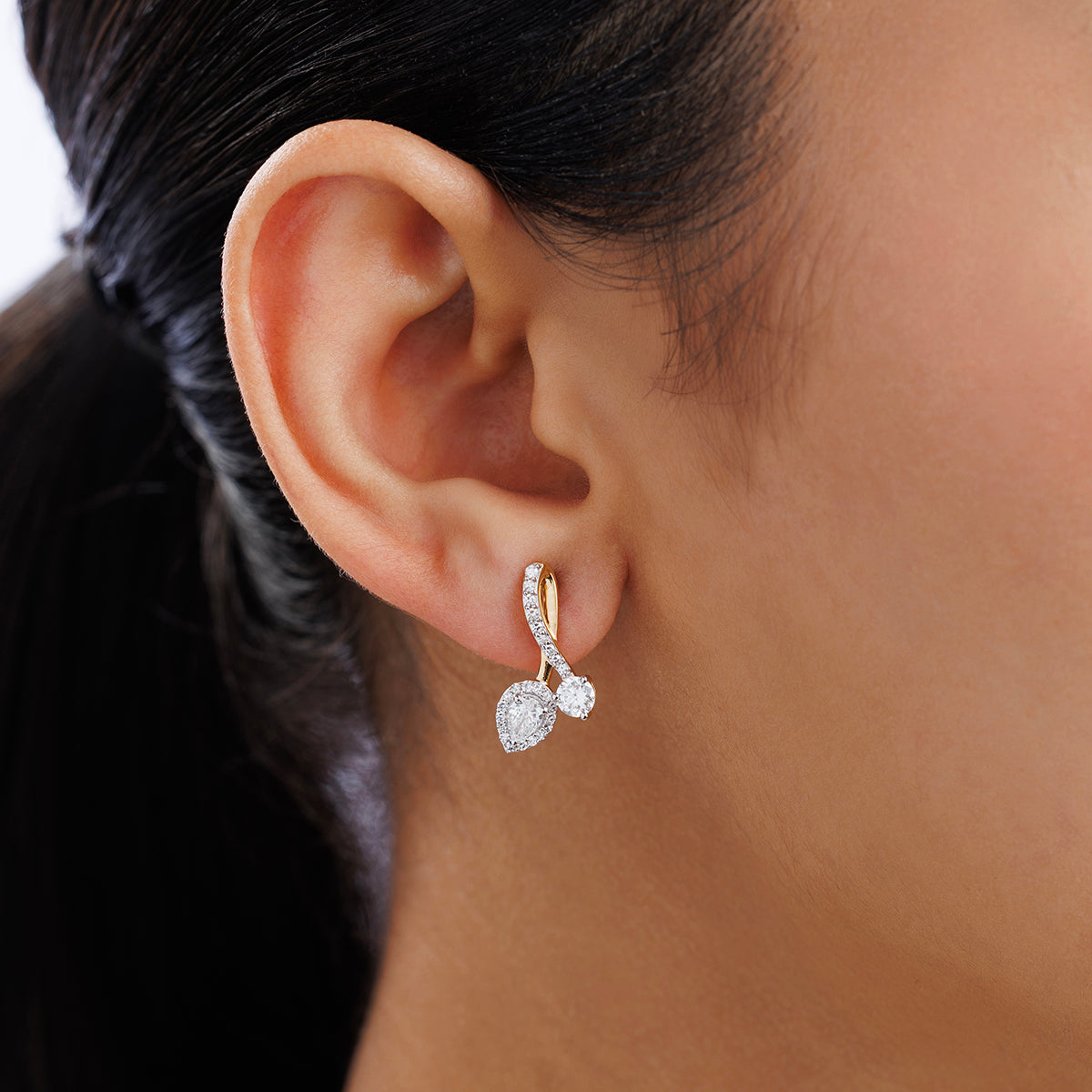 Close-up of a woman's ear wearing Keemti Jewels’ AURORA Station Hoop Earrings with two sparkling gemstones.