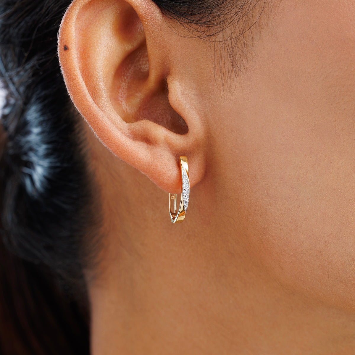 Close-up of a person’s ear wearing Keemti Jewels TWIST-AURA Hoop Earrings in textured gold and silver—everyday style.