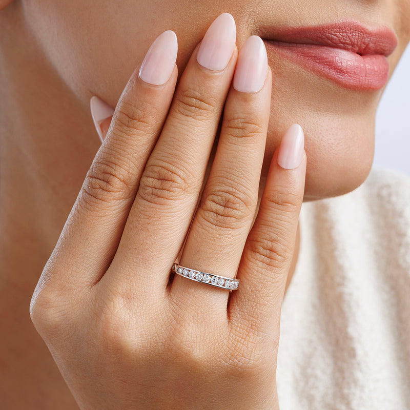 Twisted shank ring worn on finger, clear stone band in silver tone.