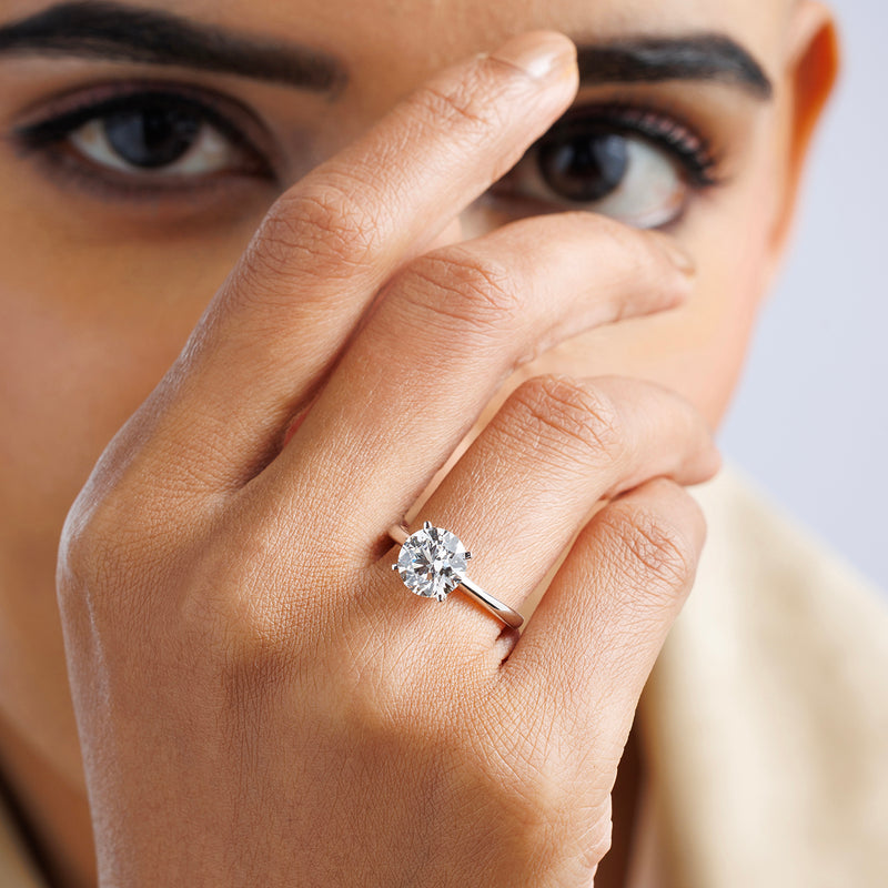 A hand near the face showcases Keemti Jewels' ELEGANT Round Solitaire RING on their finger.