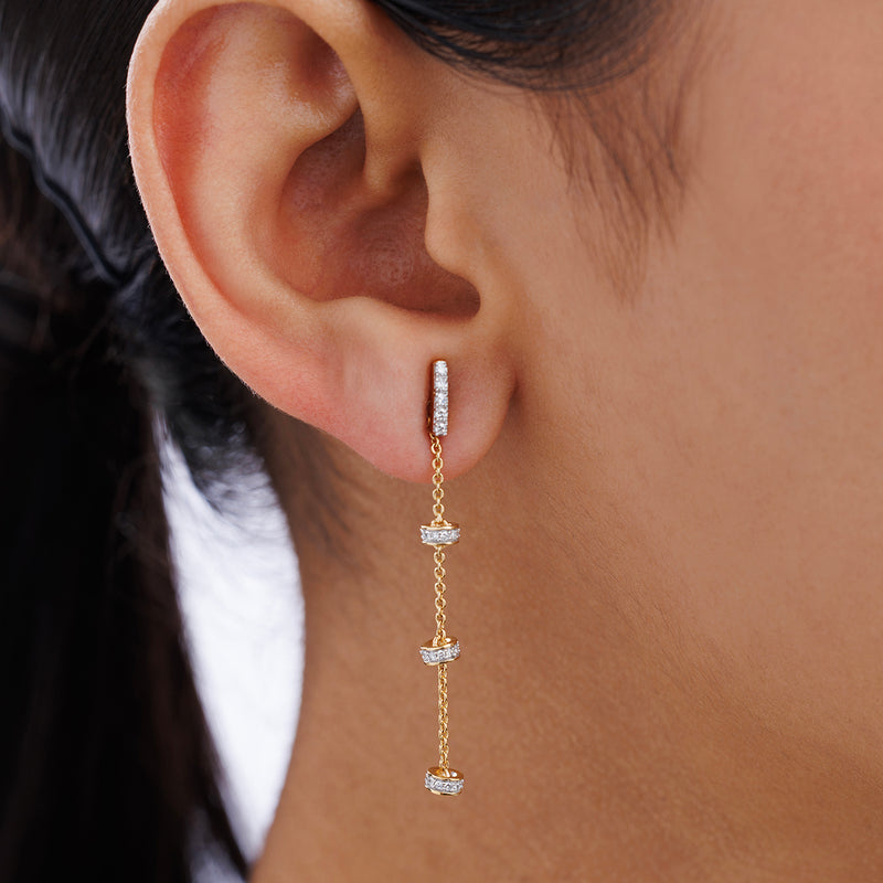 A woman’s ear adorned with Keemti Jewels TRI-CHARM Dangler Earrings featuring diamond-encrusted segments and chains.