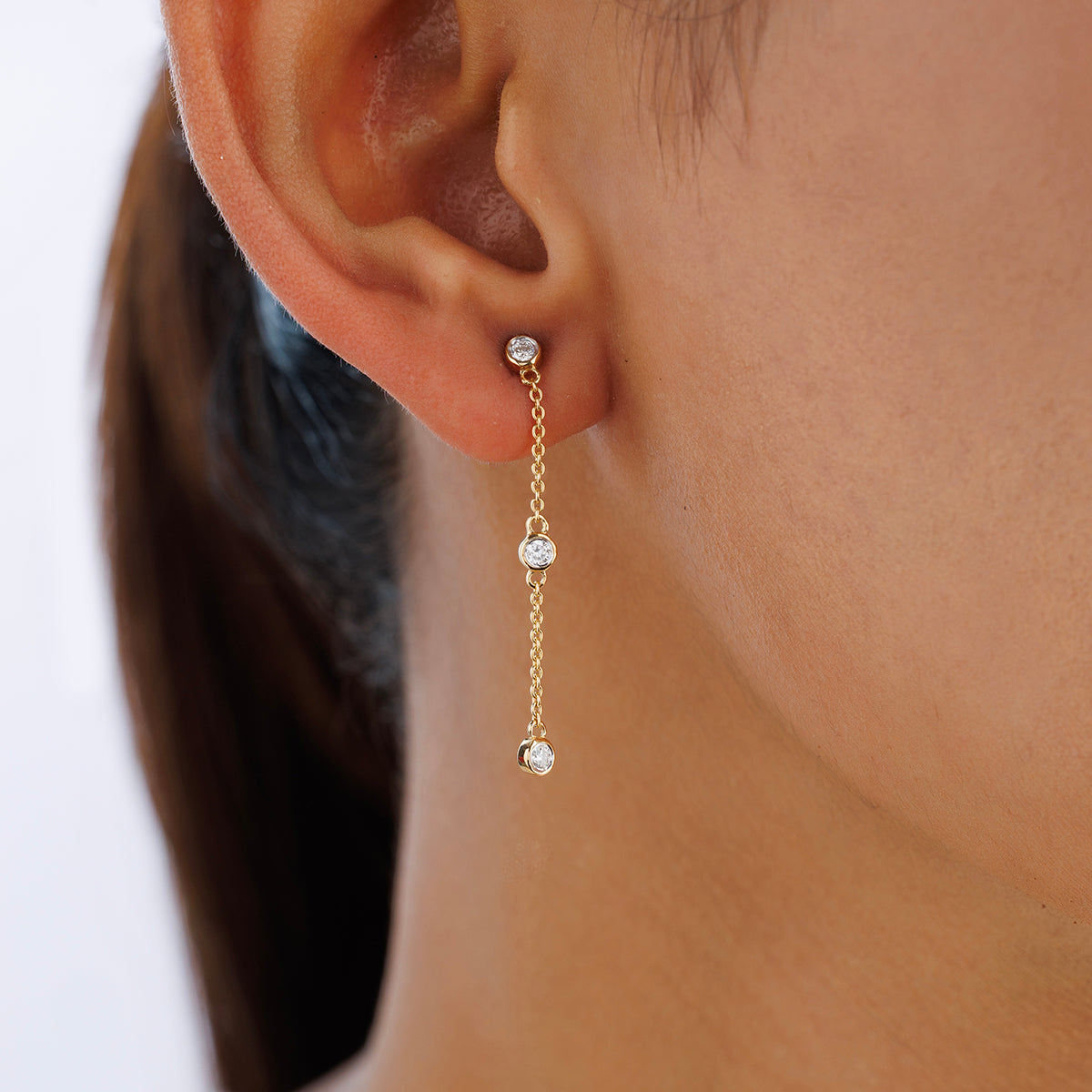 Close-up of a woman's ear wearing Keemti Jewels TRIO Trail Dangler Earrings in a delicate, dangling silhouette.
