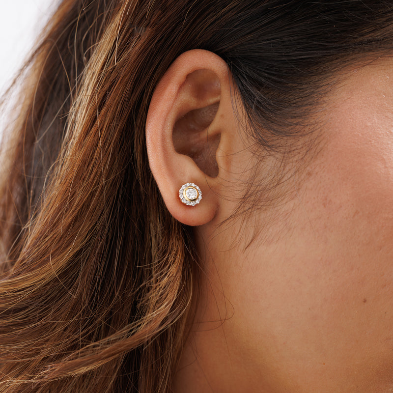 Earrings on ear: small round clear stone with silver halo and gold rim