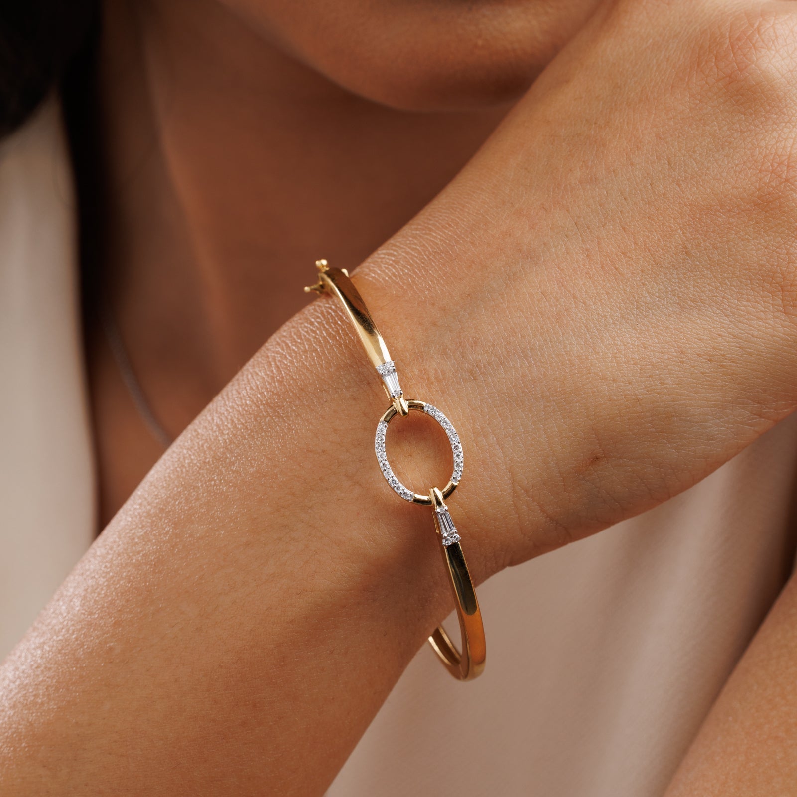 Gold-plated oval bracelet on wrist, pavé oval links with hinged clasp