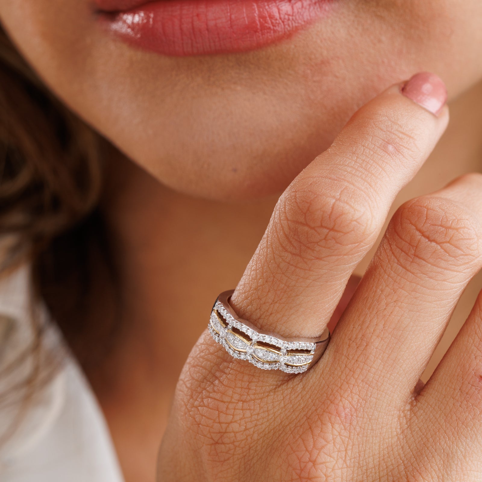 Two-tone interlinked band ring with pavé stones worn on finger, gold-toned accents