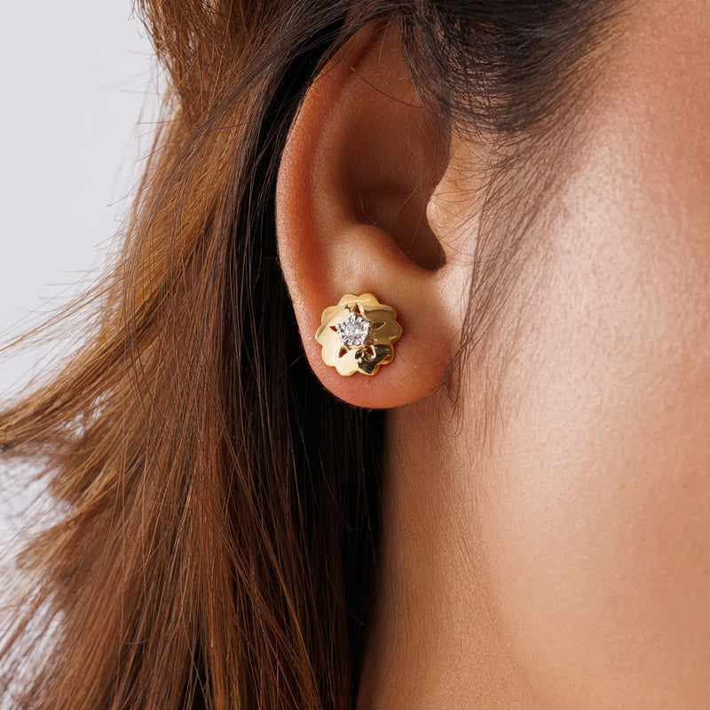 Worn starburst floral stud earrings with round clear stone on gold-tone backing