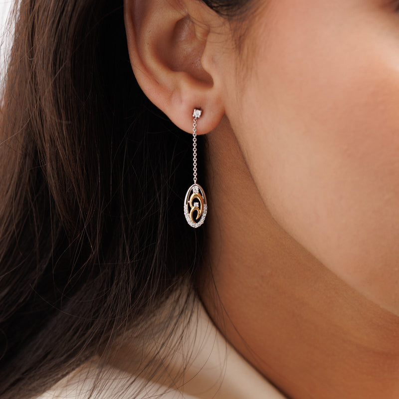 Two-tone chain drop earrings on ear, oval gold-inlay pendant with pavé detailing