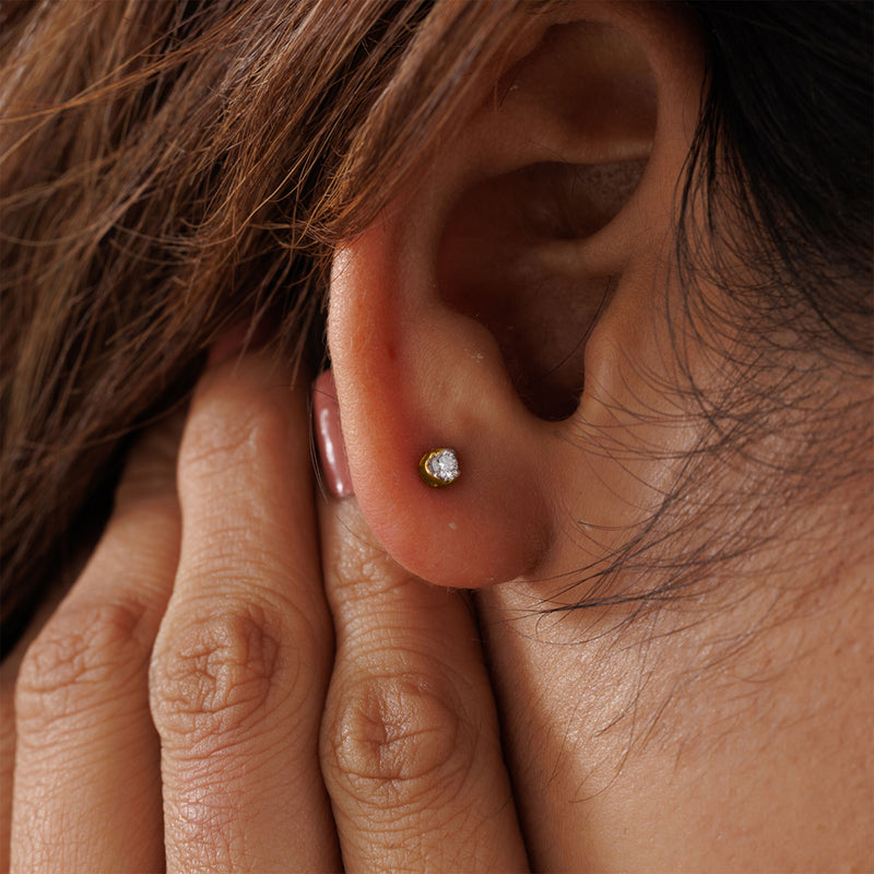 Close-up of ear with Keemti Jewels' Everyday Glow Solitaire Stud Earring; hand tucks hair by the minimal piece.