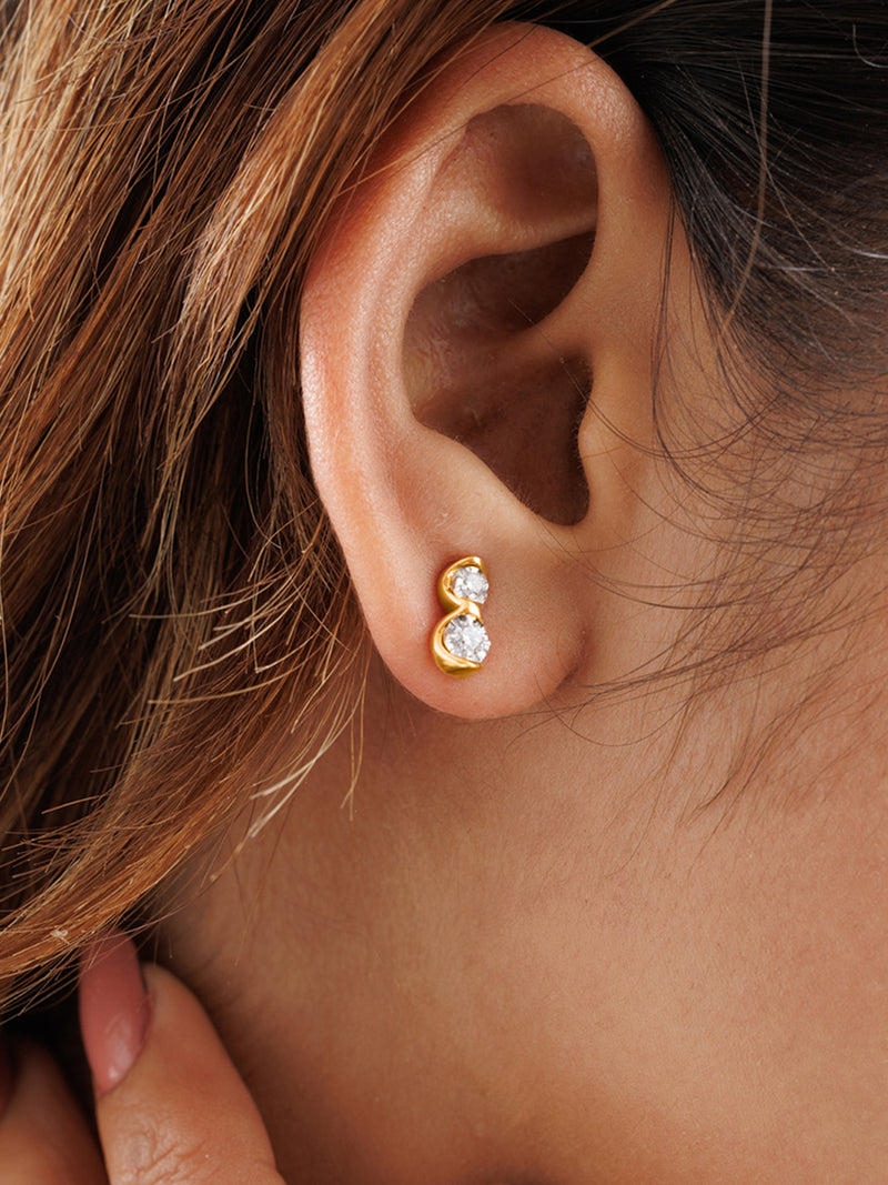 A hand brushes hair near an ear adorned with Keemti Jewels' Twin Spark Stud Earrings, shining with harmonious sparkle.