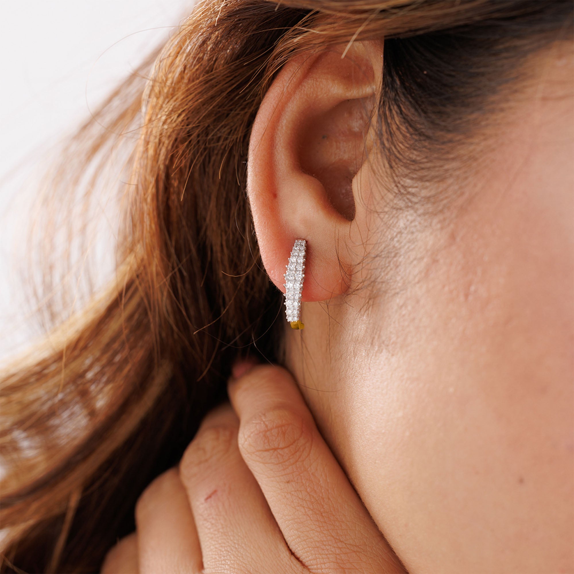Keemti Jewels Sparkling Curved Hoop Earrings elegantly worn as the model touches her neck.