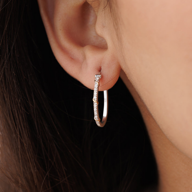 A close-up of an ear wearing Keemti Jewels' Eternal Entwine Hoop Earrings with sparkling stones on a silver hoop.