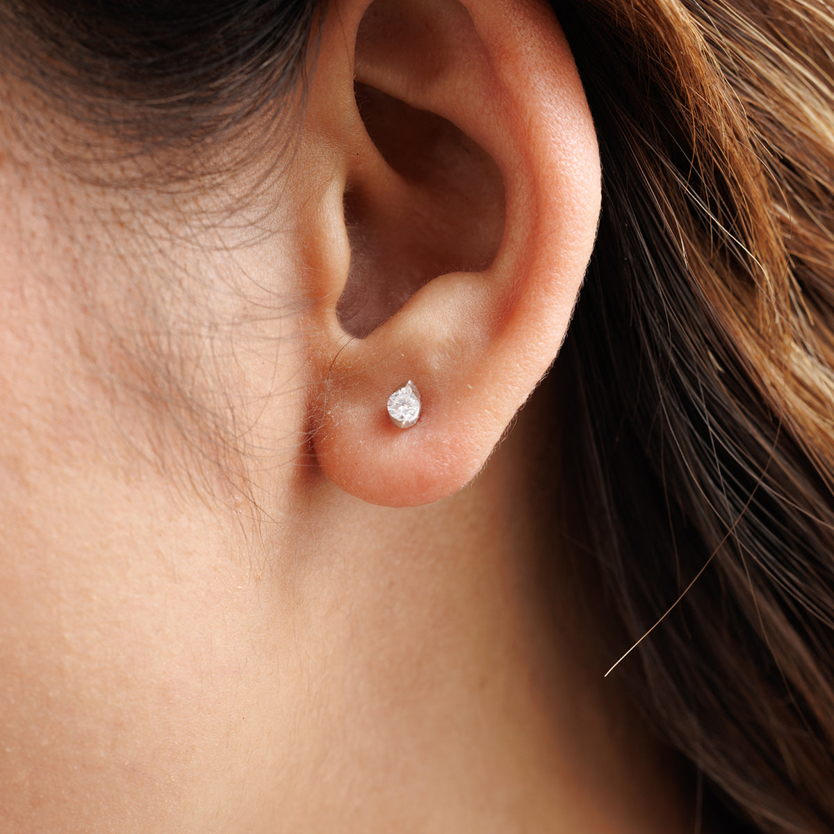 Close-up of Keemti Jewels' Forever Grace Stud Earrings, a minimalist diamond stud with brown hair partly visible.