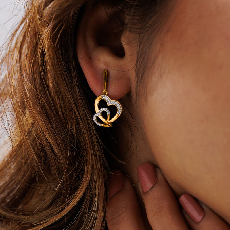 Close-up of a woman in Keemti Jewels' Tangled In Love Heart Earrings, her hand softly touching her face.