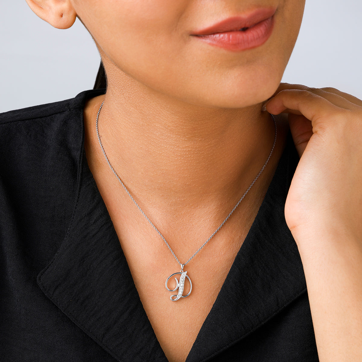 Woman wearing Keemti Jewels CLASSIC D Signature PENDANT, smiling softly with her hand near her neck.