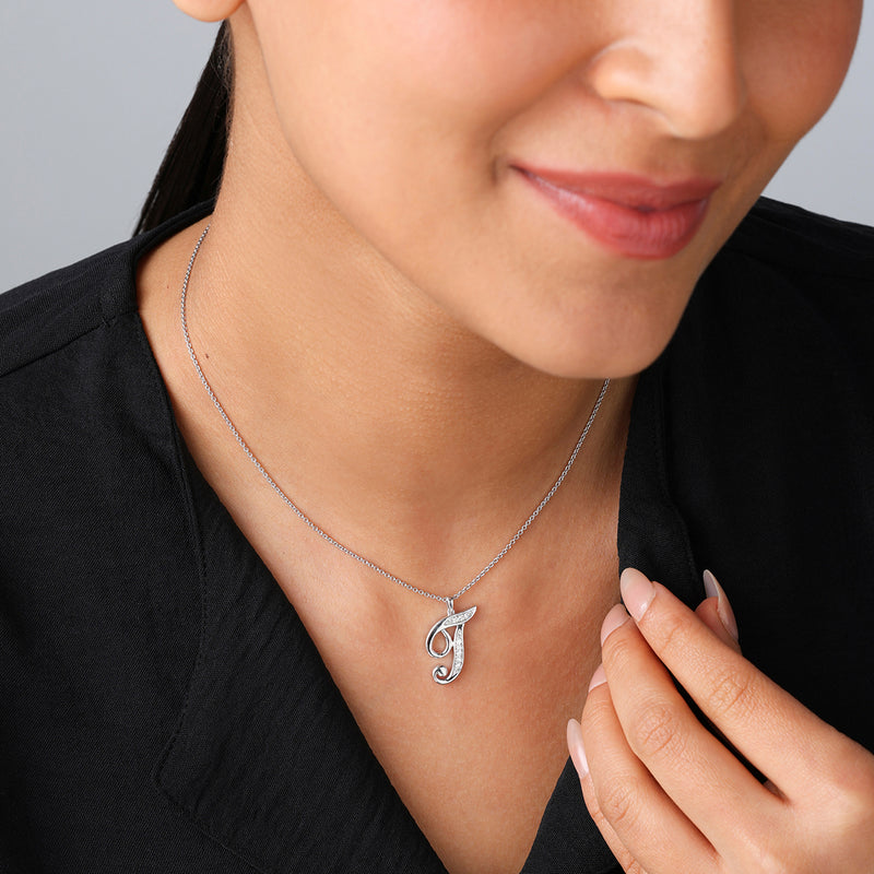 Woman wearing a black top and Keemti Jewels' CLASSIC J Signature PENDANT, gently touching her collar.