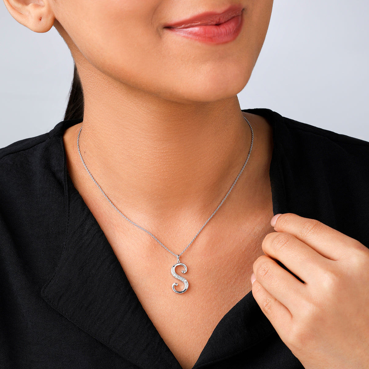 Woman wearing Keemti Jewels CLASSIC S Signature PENDANT, paired with a black top and a slight smile.