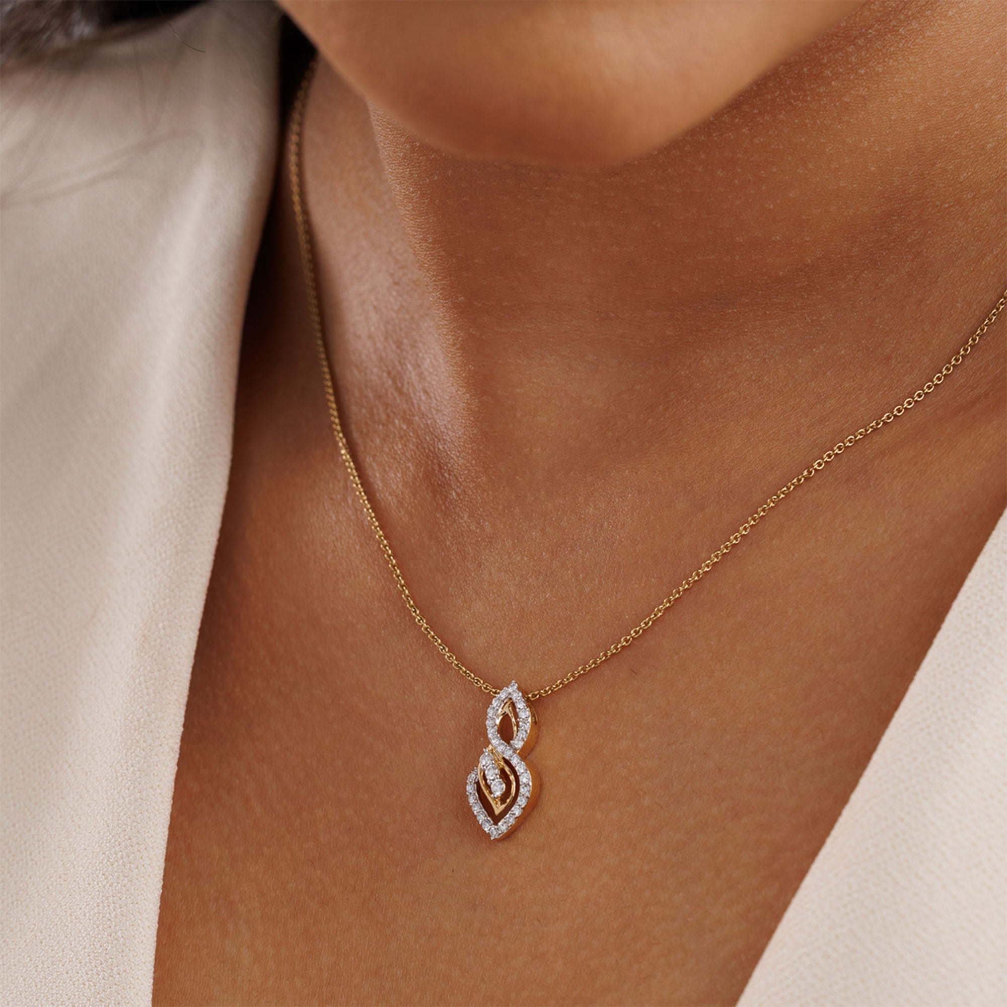 Close-up of a woman in a cream top wearing Keemti Jewels' Two-Tone Dual Loop Necklet on her neck.
