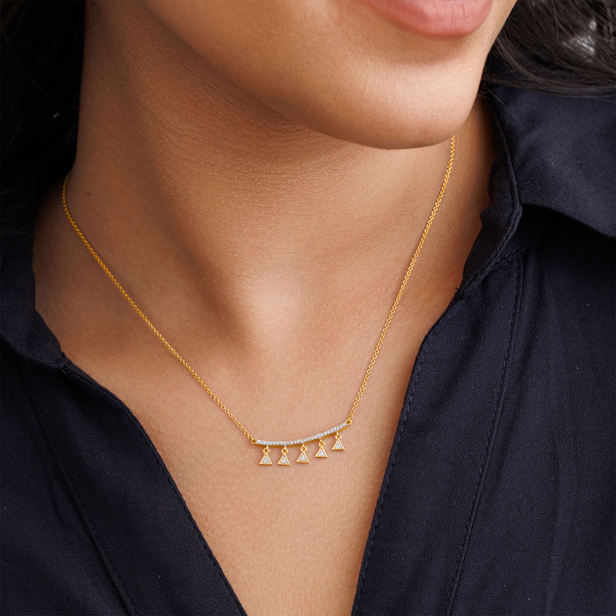 A woman in a dark collared shirt wears Keemti Jewels' Triangle Charm Drop Necklet with geometric pendants.