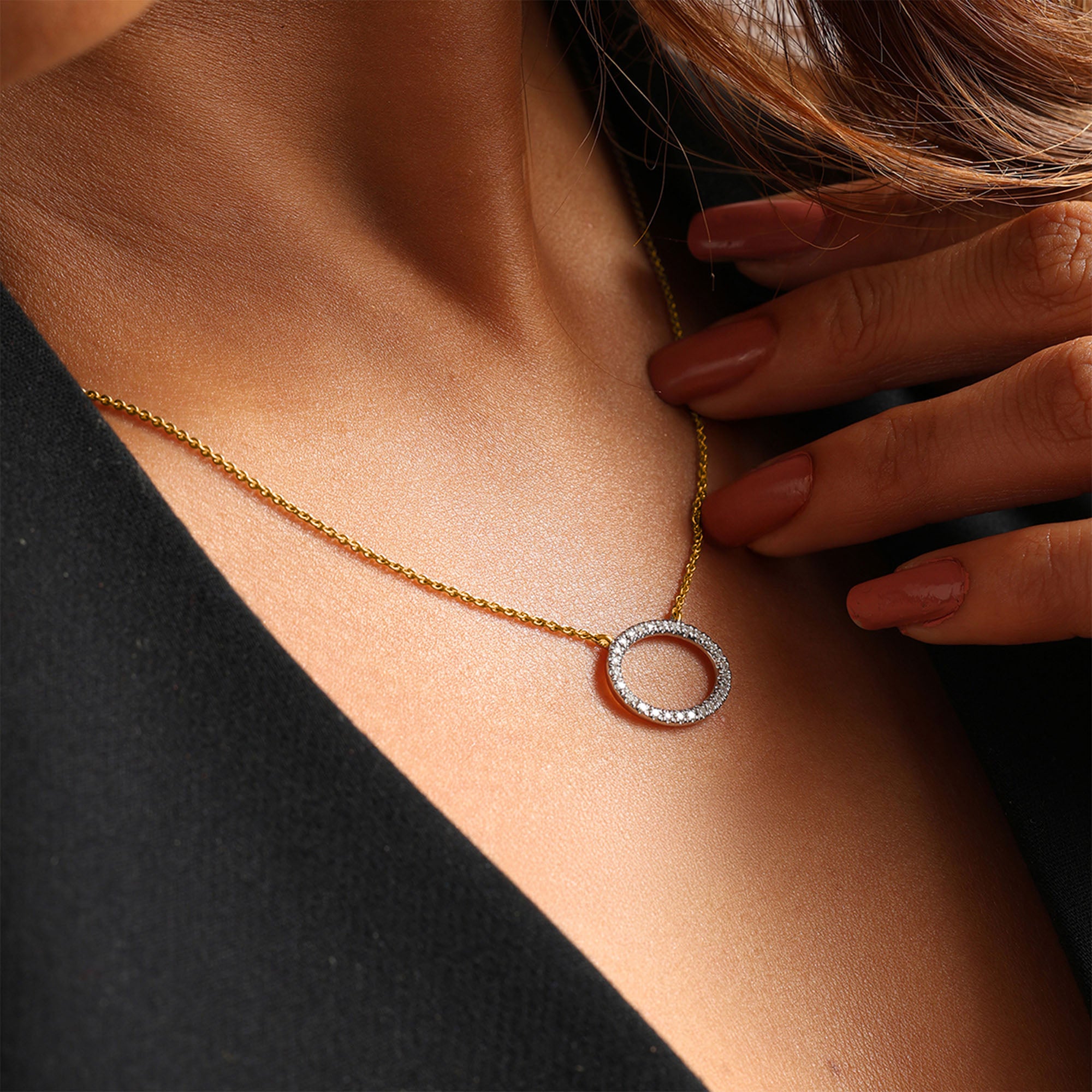 Close-up of a woman in black wearing Keemti Jewels' Classic Oval Halo Necklet with a diamond oval pendant.