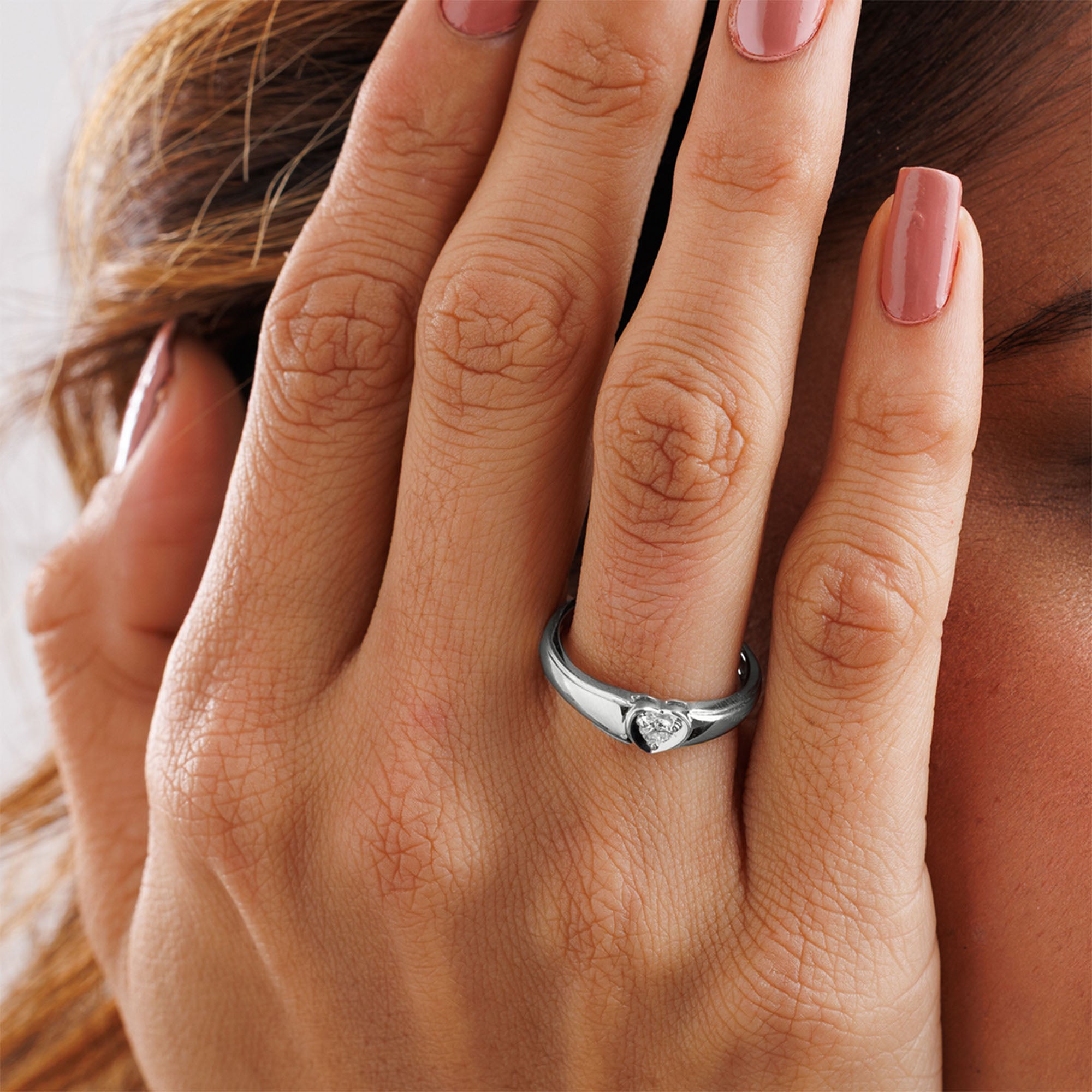 A hand with pink nails wears Keemti Jewels' Classic Pure Heart Ring, a silver band with a heart-shaped gemstone.