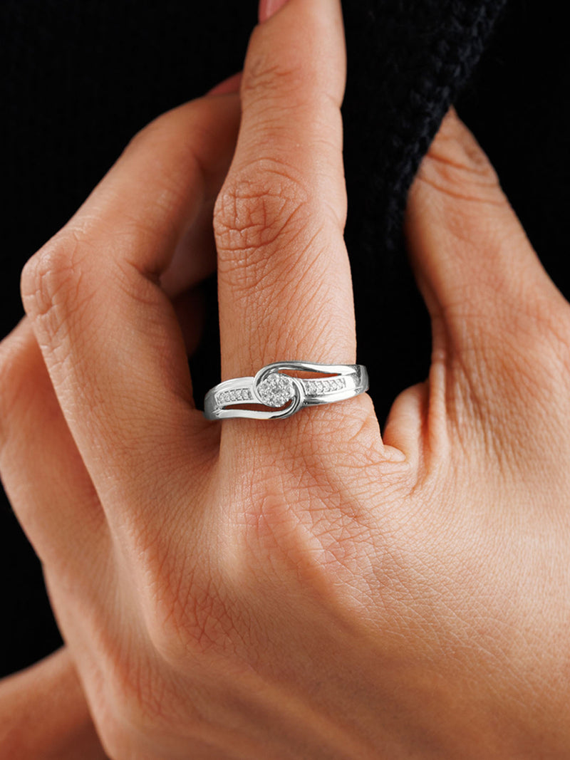 A hand with Keemti Jewels' Loop Of Light Diamond Ring, unity style, set with diamonds, holds dark fabric.