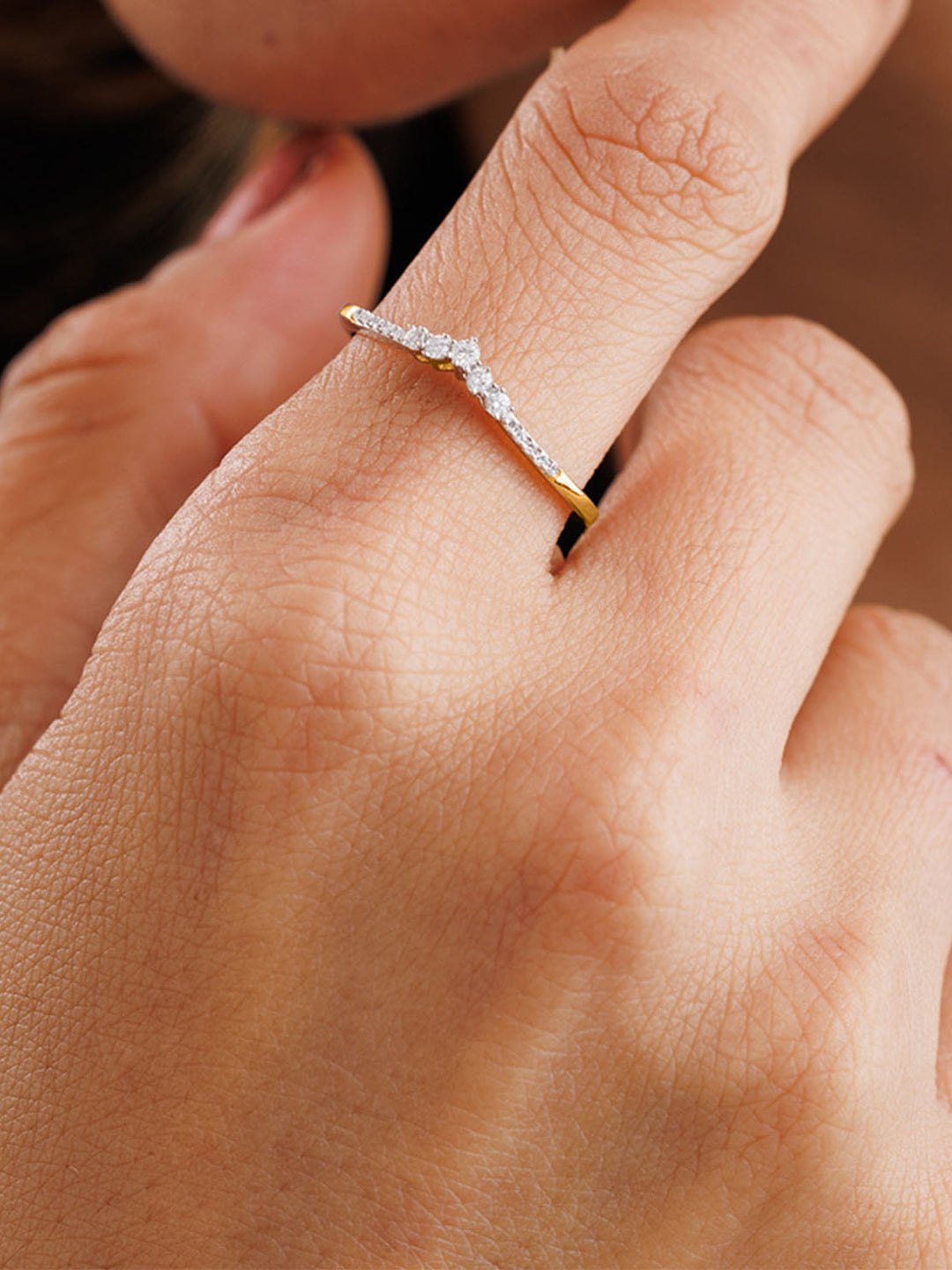A woman touches her face, wearing the Keemti Jewels Grace Arc V-Shaped Band Ring—ideal for weddings or stacking.