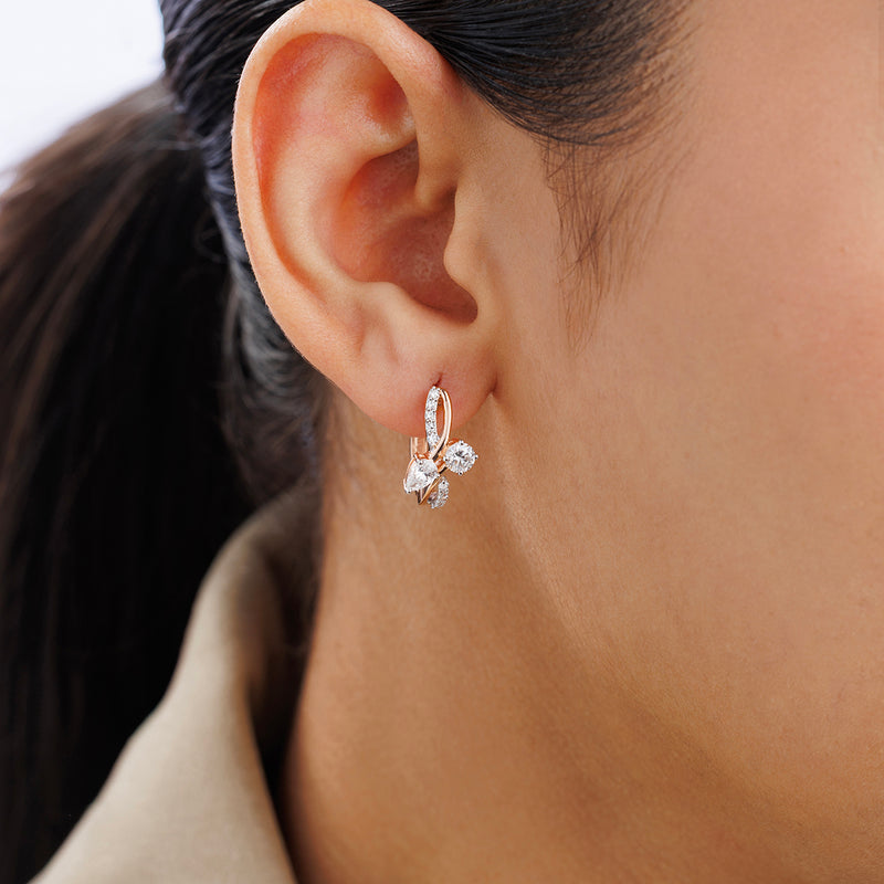 Close-up of a woman's ear wearing Keemti Jewels AERIS Flow Hoop Earrings with three clear gemstones in a floral design.
