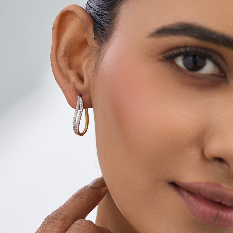 A woman in Keemti Jewels' Whisper Arc Hoop Diamond Earrings touches her neck, highlighting her ear and face.
