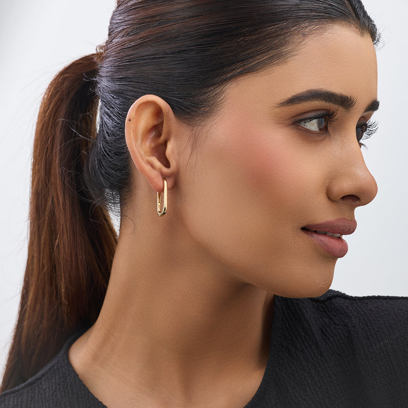 Woman with sleek ponytail wears Keemti Jewels’ Sleek Oval Diamond Hoop Earrings, facing right in a black top.