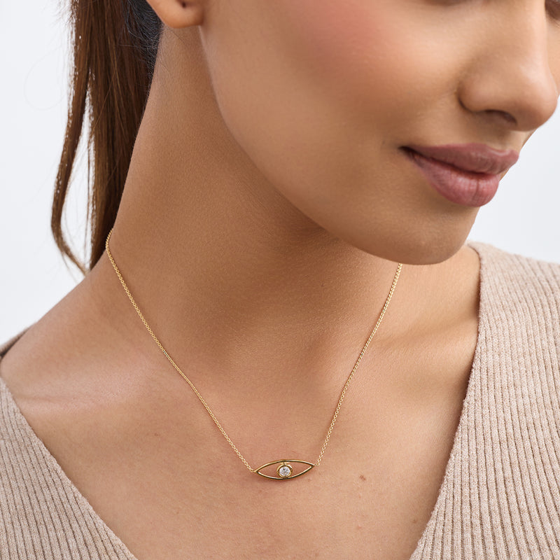A woman wears Keemti Jewels' Nazariya Glow Diamond Necklet with a beige top for a chic, protective style.