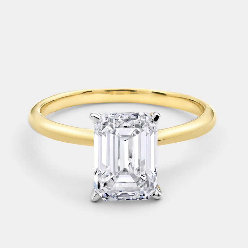 The GRACE Emerald Solitaire Ring by Keemti Jewels features a gold band with a large emerald-cut diamond in four prongs.