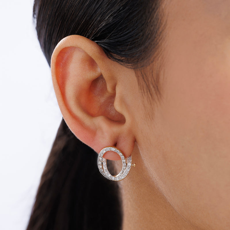 Close-up of a woman's ear wearing Keemti Jewels' CELESTE Orbit Hoop Earrings against a plain background.