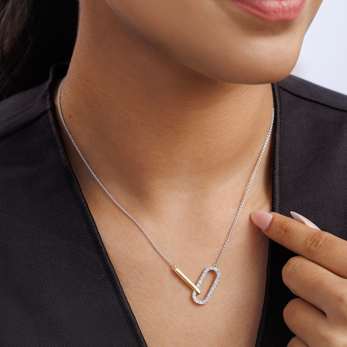 Woman wears the CHIC Interlocking Link NECKLET by Keemti Jewels, gently touching its gold and silver links.