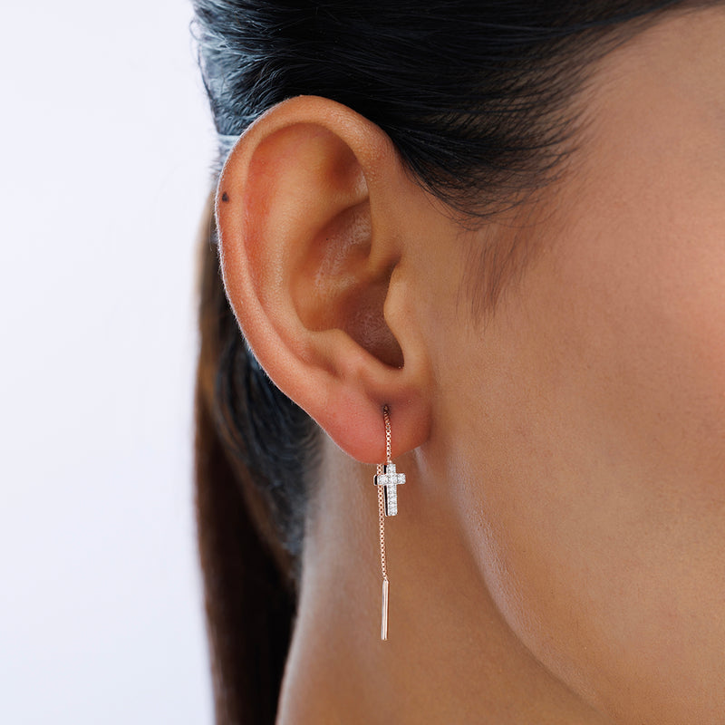 A close-up of a woman's ear wearing Keemti Jewels SACRED Cross Sui Dhaga Earrings with a thin chain.