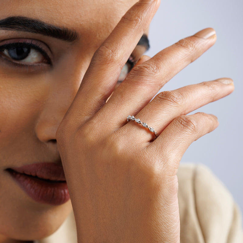 A woman with a soft smile showcases the Keemti Jewels CROWN Curve Diamond Ring on her finger near her face.