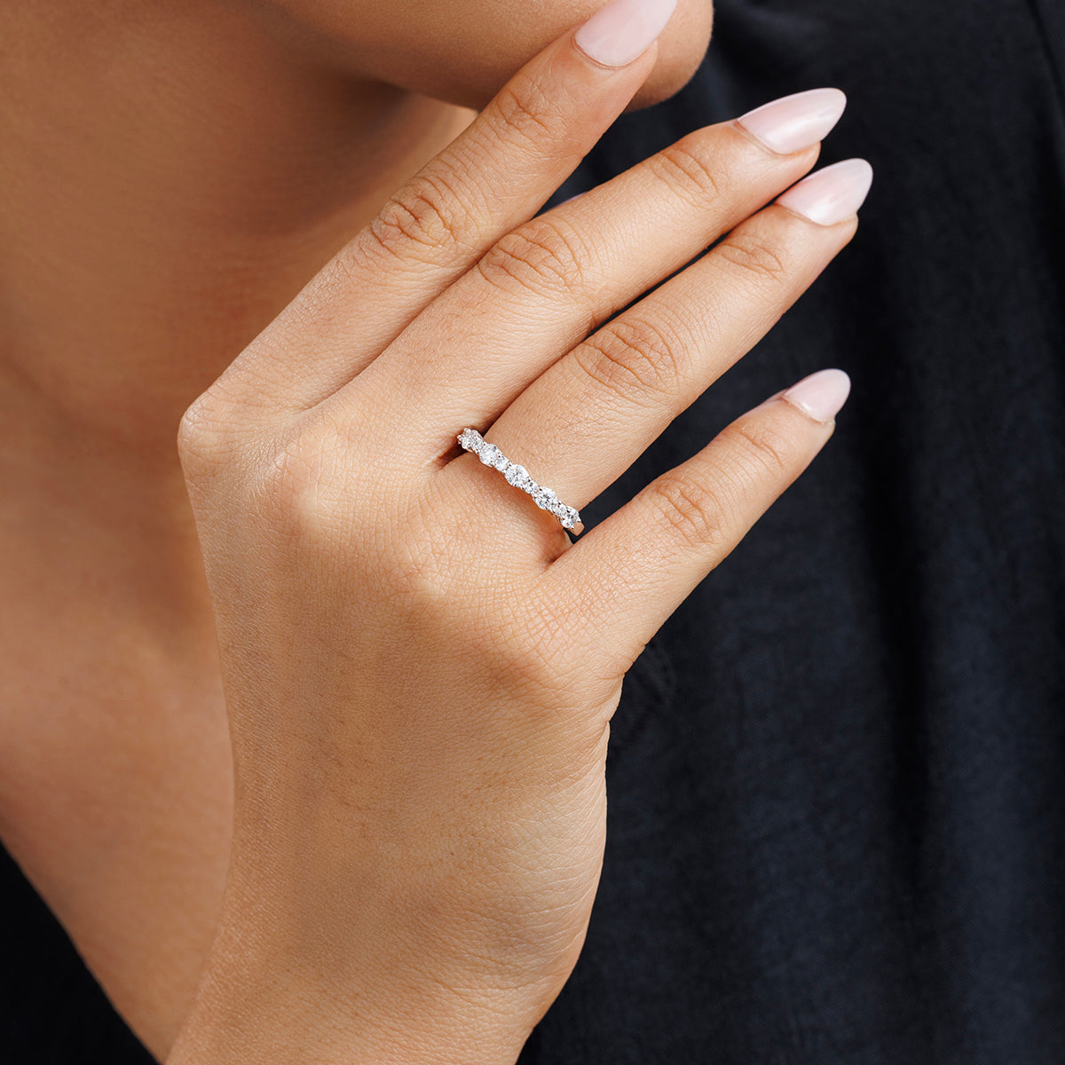 A hand with light pink nails wears the GEOMETRIC Eternity RING by Keemti Jewels, dark shirt in the background.