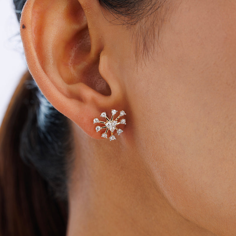 A close-up of a woman wearing Keemti Jewels' SNOWFALL Stud Earrings—gold snowflake studs with clear gemstones.