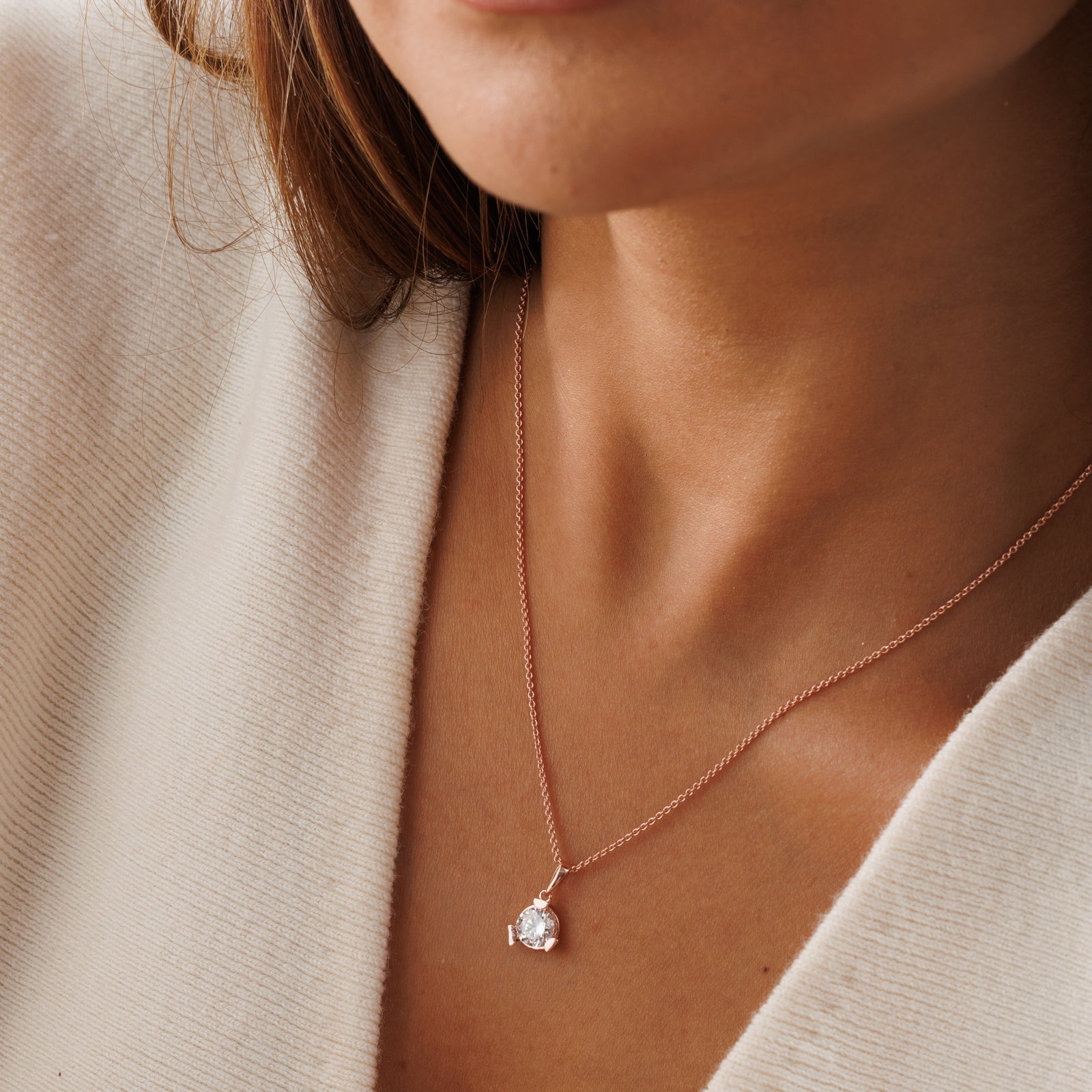 Rose-gold diamond necklet worn close-up; round pendant on fine chain