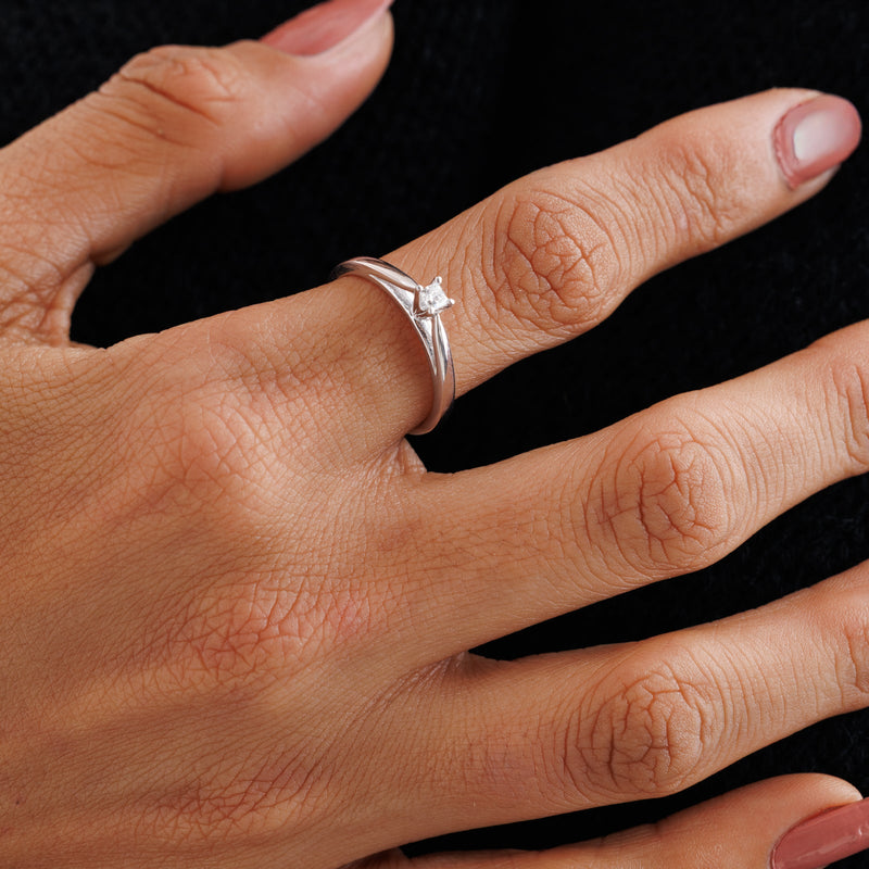 Princess-cut diamond ring on finger, silver-tone 4-prong setting
