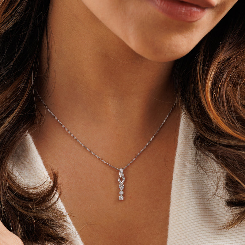 Three-stone twirl drop necklace on neckline: silver chain with sparkling swirl pendant