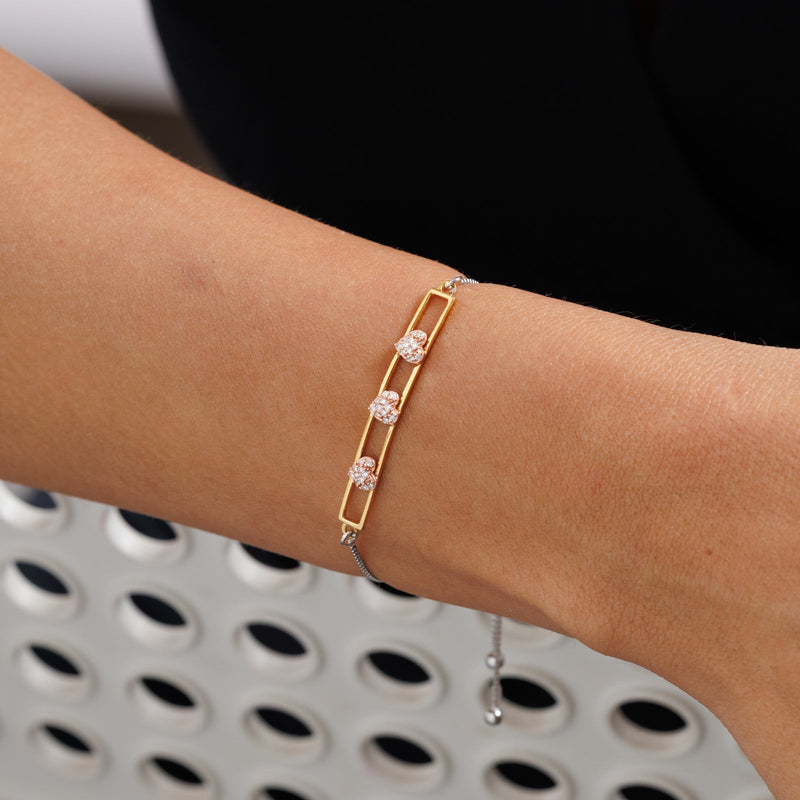 Gold-tone bolo bracelet with three heart pavé stones on wrist
