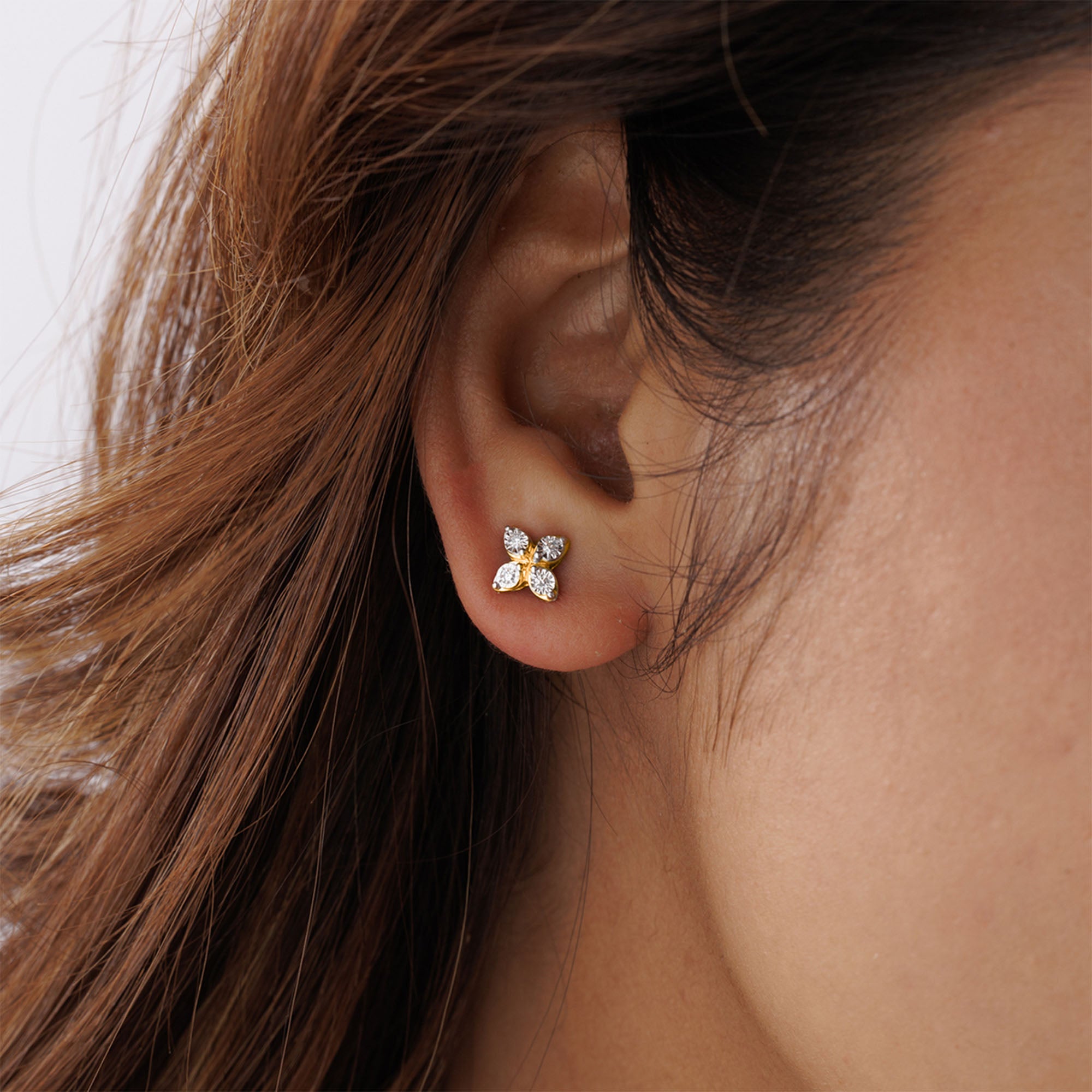 Close-up of a woman's ear wearing Keemti Jewels Clover Spark Stud Earrings; gold, diamond, floral design visible.