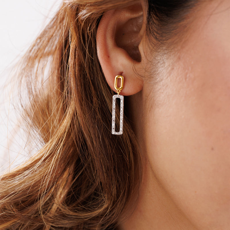 Keemti Jewels' Geometric Diamond Drop Earrings dangle elegantly as wavy hair frames a woman's ear.