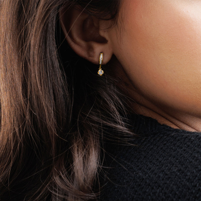 Close-up of a woman's ear wearing Keemti Jewels Mini Hoop Drop Earrings with a dangling clear gemstone.