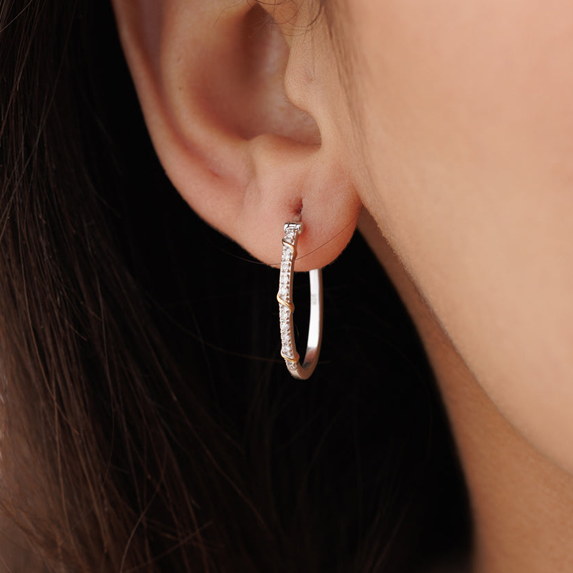 A close-up of an ear wearing Keemti Jewels' Eternal Entwine Hoop Earrings with sparkling stones on a silver hoop.