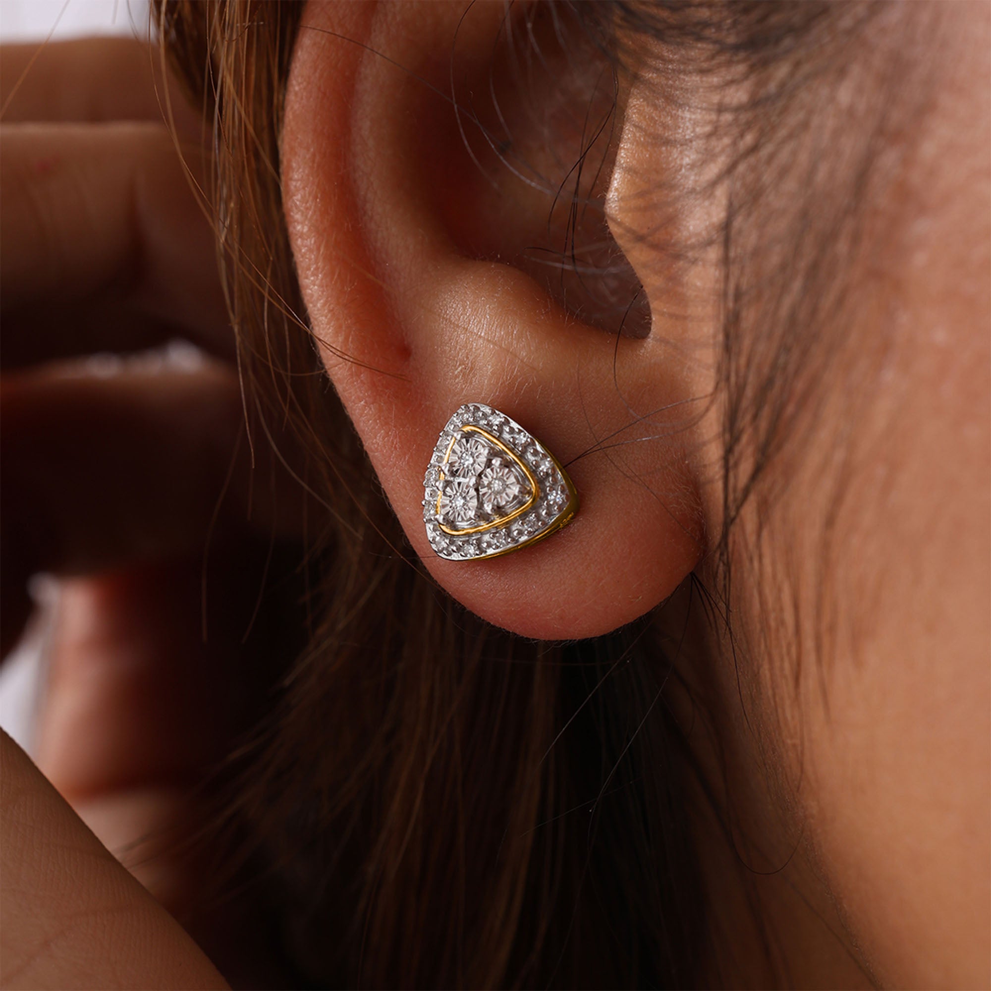 Close-up of a woman's ear wearing Keemti Jewels' Two-Tone Triangular Halo Stud Earrings.