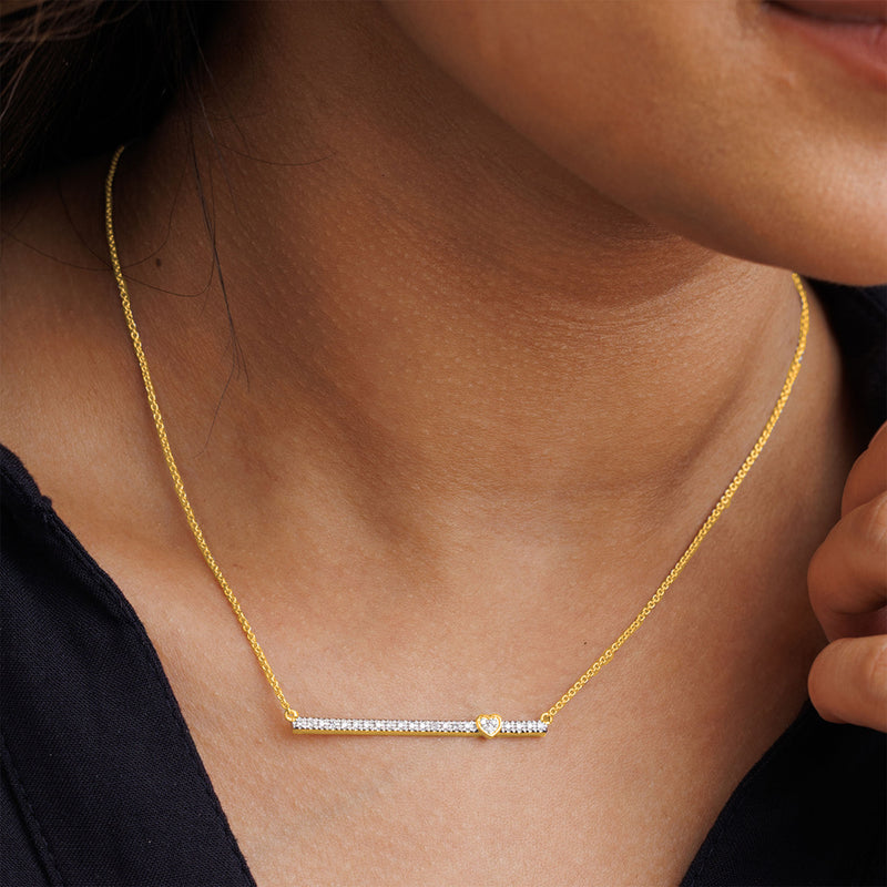 A woman wears Keemti Jewels' Linear Love Necklet with a horizontal diamond bar, paired with a dark top.
